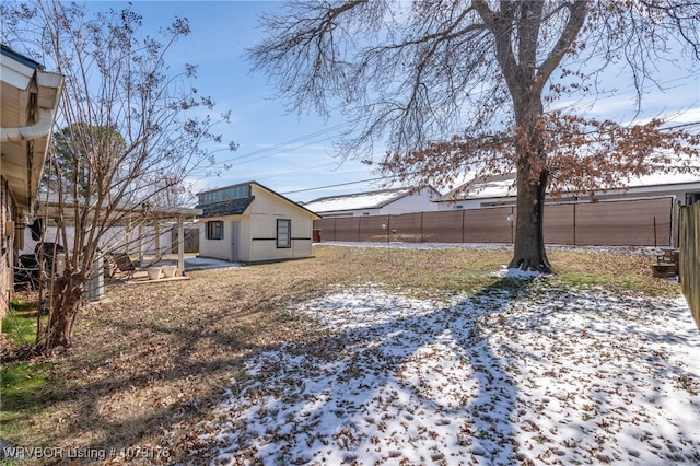 yard layered in snow with an outbuilding and a fenced backyard