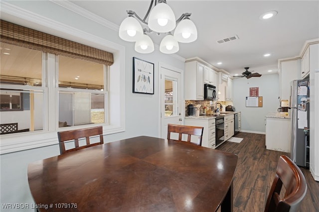 dining space with dark wood finished floors, recessed lighting, ceiling fan with notable chandelier, and ornamental molding