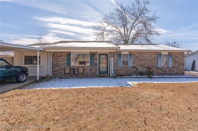 single story home featuring an attached carport, a porch, and brick siding