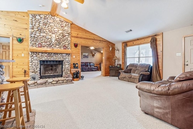 carpeted living room with ceiling fan, wood walls, a fireplace, and lofted ceiling with beams