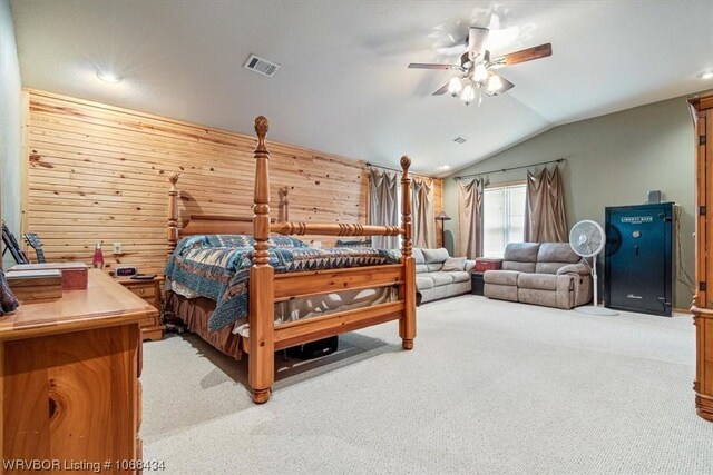 bedroom featuring ceiling fan, light colored carpet, wooden walls, and vaulted ceiling