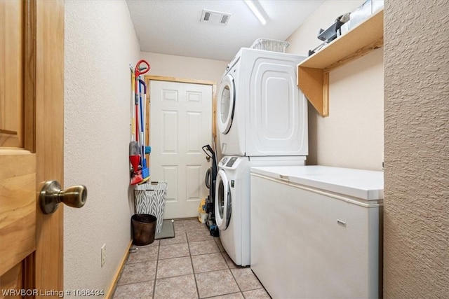 laundry area featuring stacked washer and dryer and light tile patterned flooring