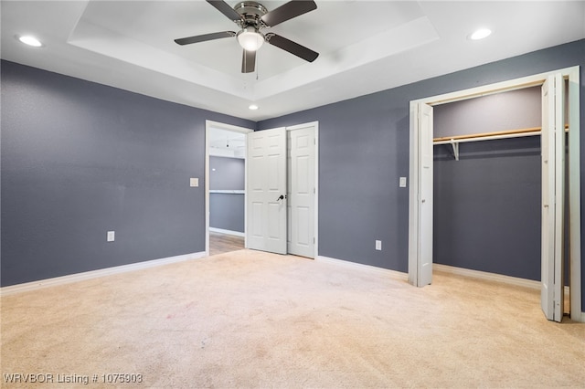 unfurnished bedroom with a tray ceiling, ceiling fan, and light colored carpet