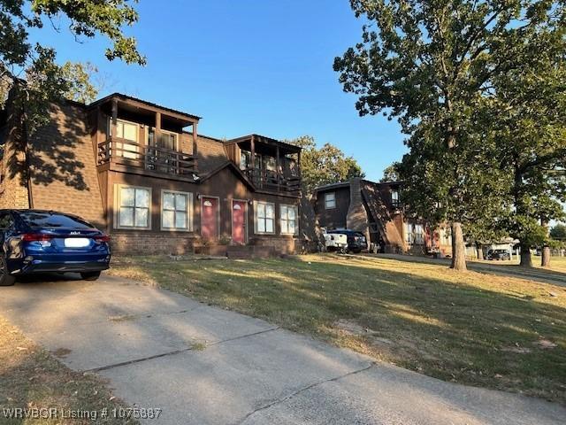 view of front of home with a balcony and a front yard