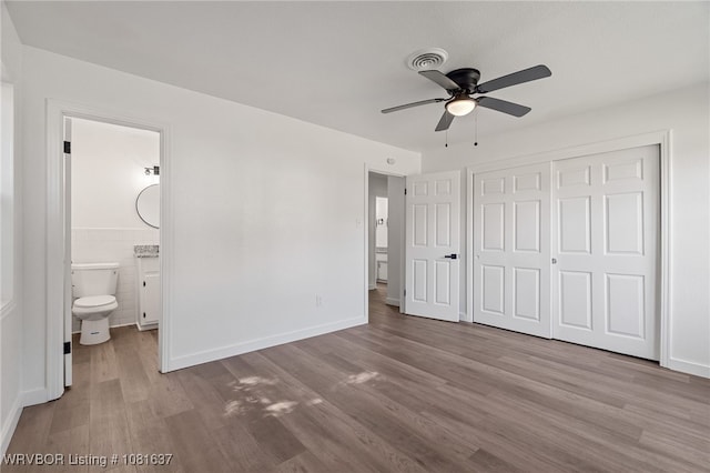 123 Oak St, Alma, AR 72921 - unfurnished bedroom with wood finished floors, a closet, ensuite bathroom, wainscoting, and tile walls