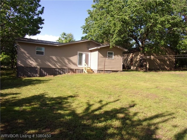 rear view of property with entry steps and a lawn