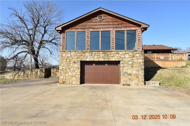 view of front facade with concrete driveway, a garage, and stone siding