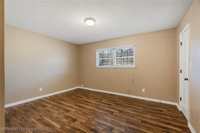 empty room with a textured ceiling and dark wood-type flooring