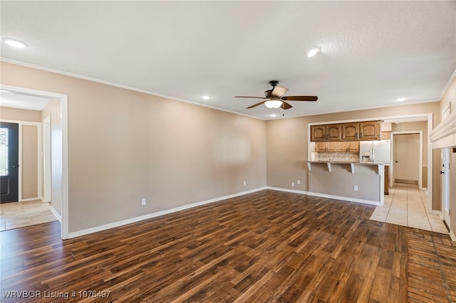 unfurnished living room featuring dark hardwood / wood-style floors, ceiling fan, and crown molding