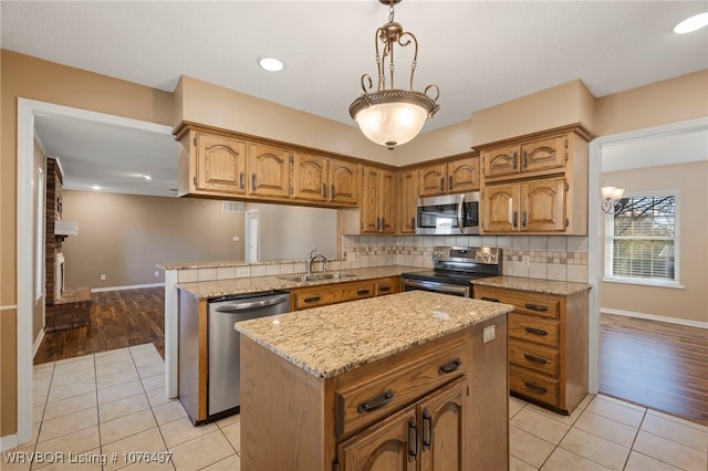 kitchen featuring appliances with stainless steel finishes, sink, light tile patterned floors, a center island, and hanging light fixtures