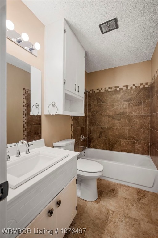 full bathroom with tiled shower / bath combo, toilet, a textured ceiling, and vanity