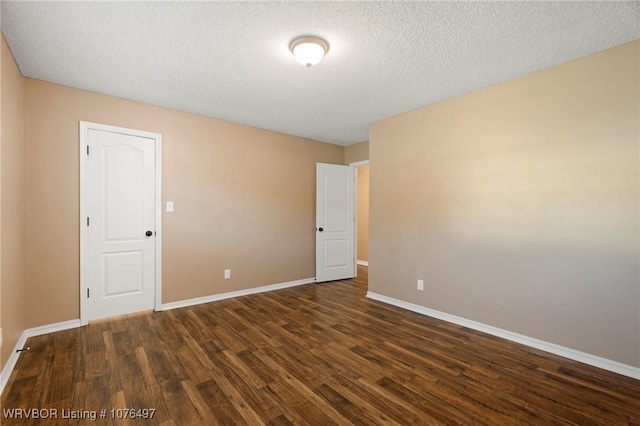 spare room with a textured ceiling and dark wood-type flooring