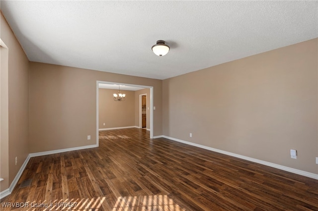 spare room with dark wood-type flooring and a notable chandelier