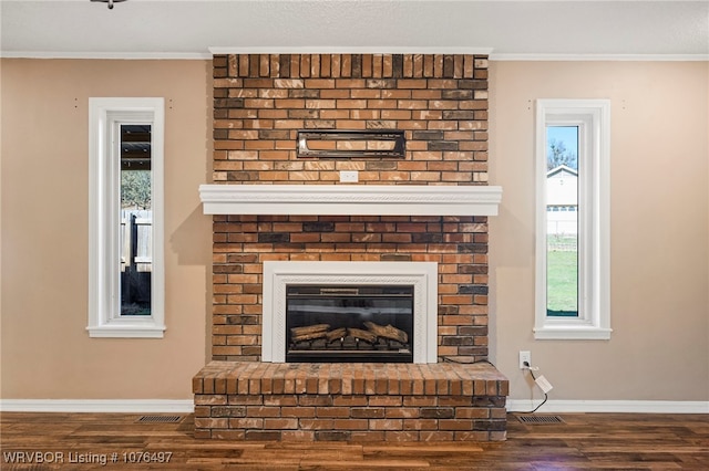 interior details featuring hardwood / wood-style flooring, a brick fireplace, and crown molding