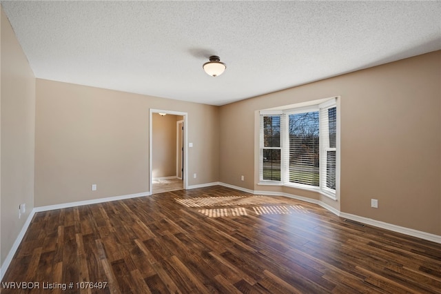 spare room with dark wood-type flooring and a textured ceiling