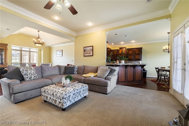 carpeted living room with ceiling fan with notable chandelier and crown molding