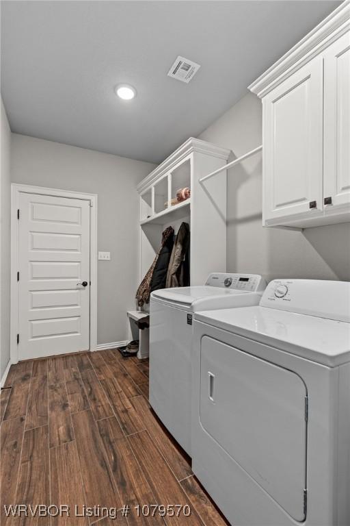 laundry area with baseboards, visible vents, cabinet space, dark wood-type flooring, and washing machine and dryer