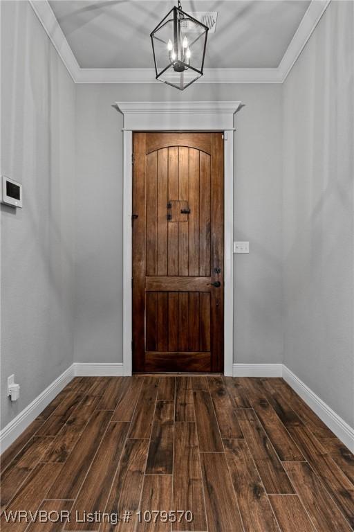 entryway with dark wood finished floors, crown molding, baseboards, and a chandelier