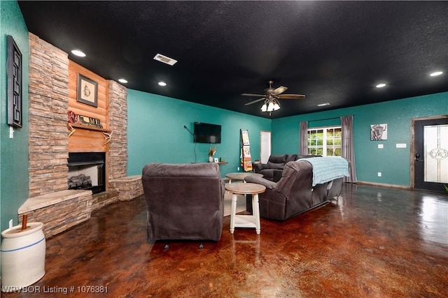 living room featuring a fireplace, a textured ceiling, and ceiling fan