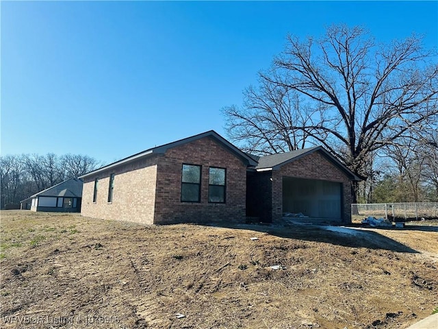 single story home featuring brick siding, a garage, and fence