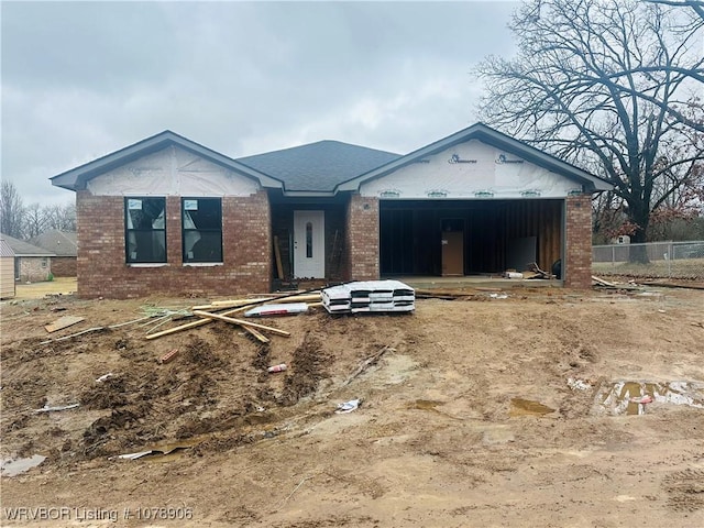 unfinished property with a garage, brick siding, and fence