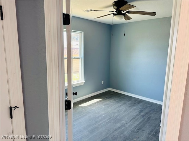spare room with wood finished floors, a ceiling fan, and baseboards