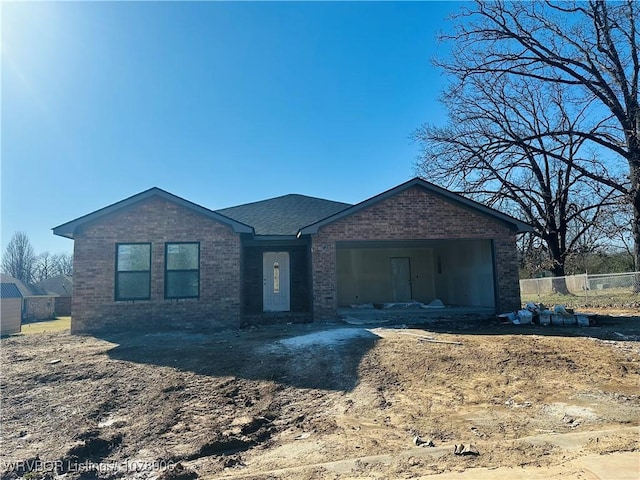 view of front of house with brick siding, a garage, and fence