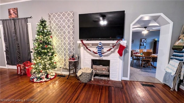 living room with hardwood / wood-style flooring, ceiling fan, and a brick fireplace