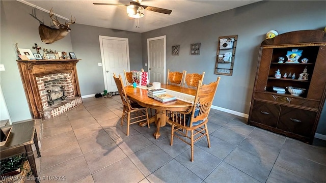 tiled dining area featuring ceiling fan and a fireplace