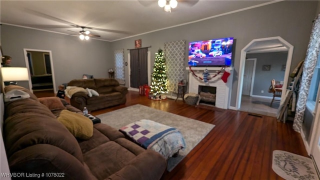 living room featuring a fireplace, hardwood / wood-style floors, ceiling fan, and crown molding