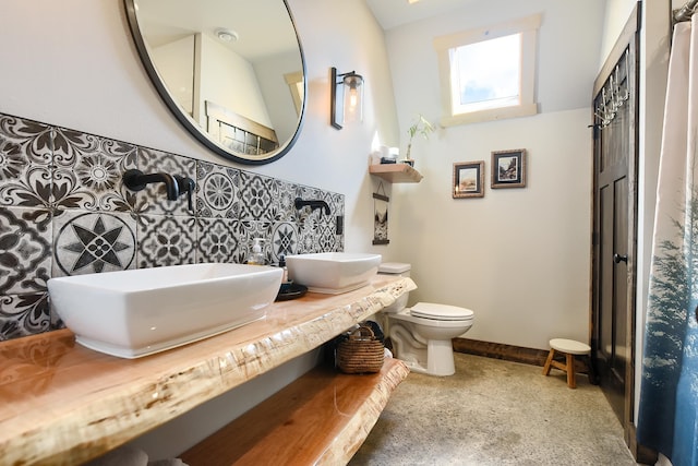 bathroom featuring toilet, double vanity, and tile walls