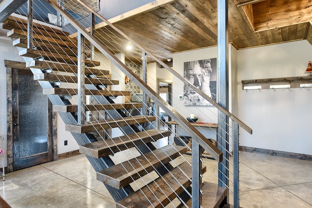 staircase featuring concrete floors and wood ceiling