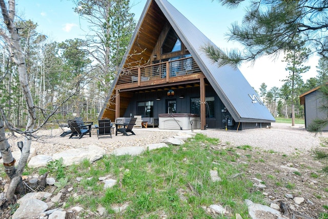 back of house featuring a balcony, a hot tub, and a patio area