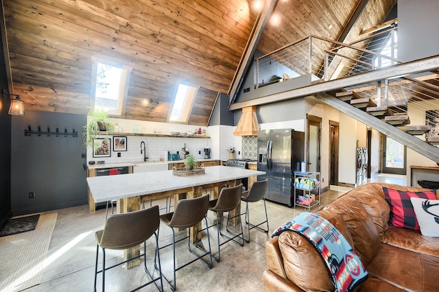 kitchen featuring a skylight, backsplash, stainless steel appliances, wooden ceiling, and high vaulted ceiling