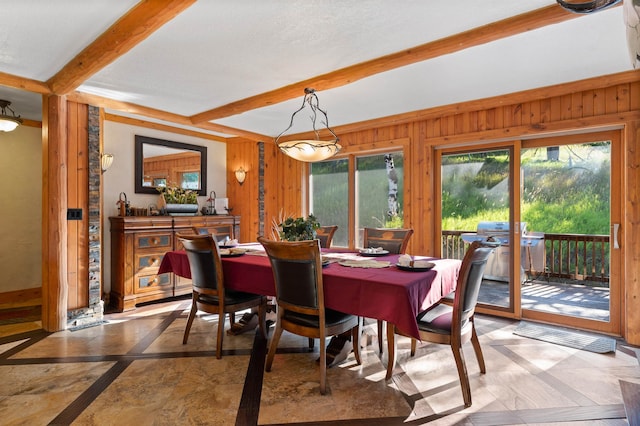 dining area with wood walls and beam ceiling