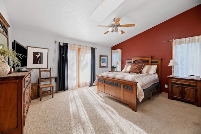 carpeted bedroom featuring vaulted ceiling with skylight and ceiling fan