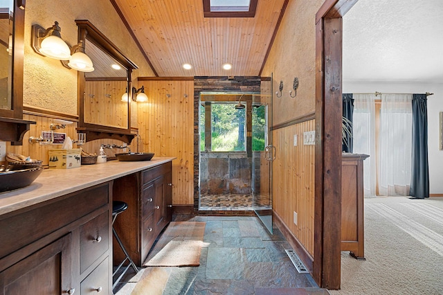 bathroom featuring a shower with shower door, wooden walls, vanity, wood ceiling, and lofted ceiling with skylight