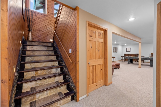 staircase with wood walls, light carpet, and pool table