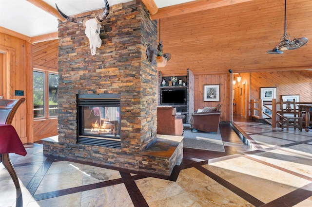 living room with wood walls, dark tile flooring, high vaulted ceiling, and a fireplace