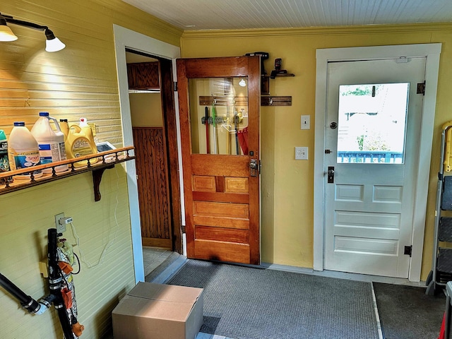 doorway to outside with wood walls and crown molding