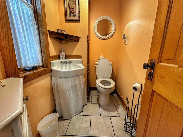 bathroom featuring toilet, sink, and tile flooring