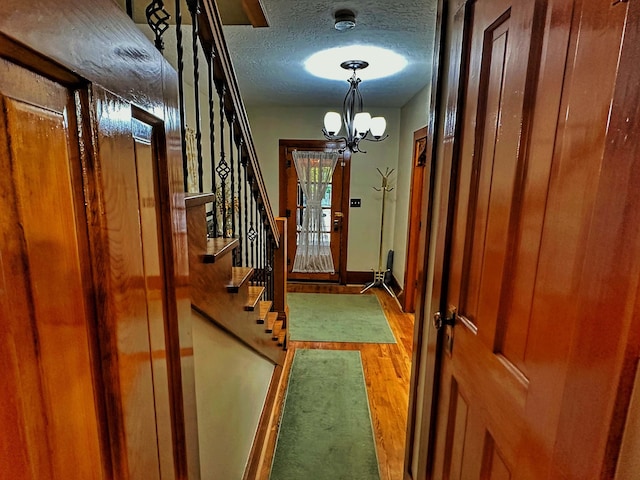 entryway with an inviting chandelier, a textured ceiling, and hardwood / wood-style floors