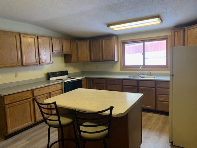 kitchen featuring white appliances, a kitchen island, sink, and light hardwood / wood-style floors