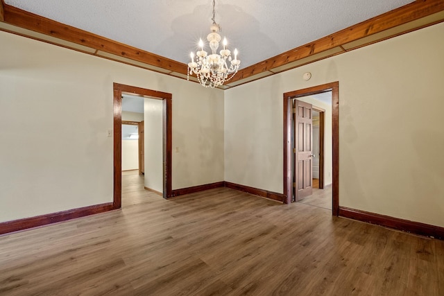 spare room with a textured ceiling, an inviting chandelier, and wood-type flooring