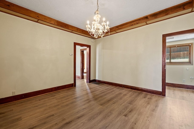 spare room featuring a textured ceiling, a chandelier, and hardwood / wood-style floors