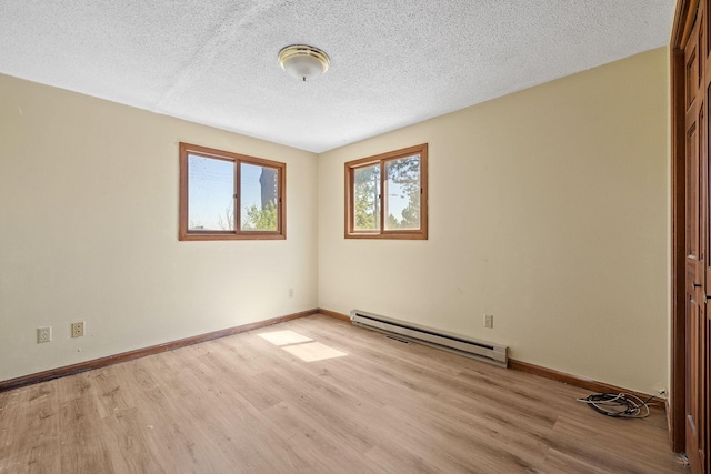 empty room with light wood-type flooring, a textured ceiling, and baseboard heating