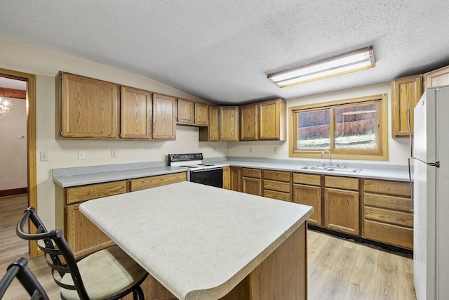 kitchen with light wood-type flooring, white appliances, a breakfast bar area, and sink