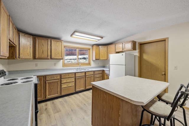 kitchen featuring white appliances, light hardwood / wood-style flooring, sink, and a textured ceiling