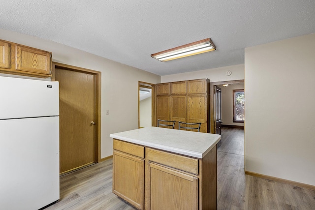 kitchen featuring a textured ceiling, a center island, white fridge, and light wood-type flooring