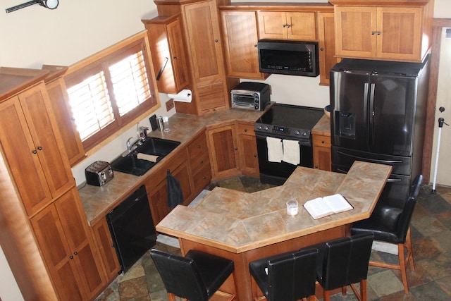 kitchen featuring a breakfast bar, sink, and black appliances